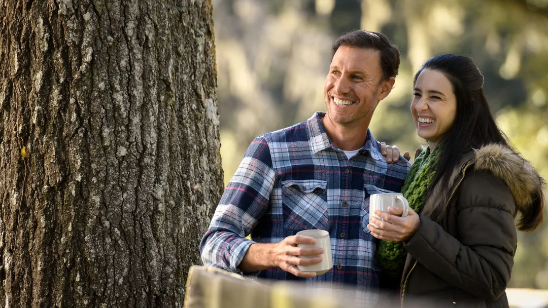 A couple holding mugs while outdoors in the winter.