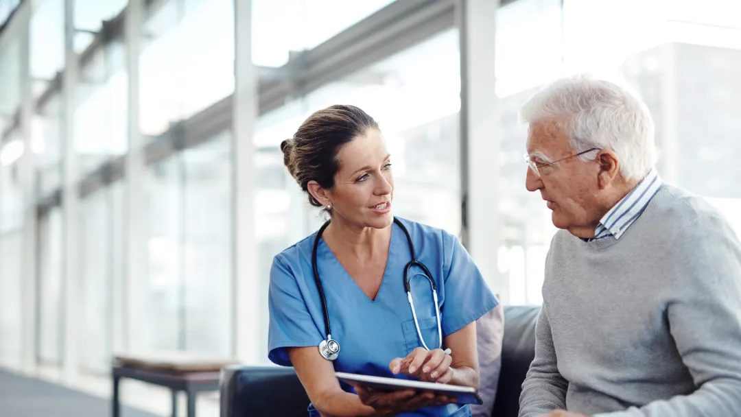 Nurse talking with older man at the hospital.