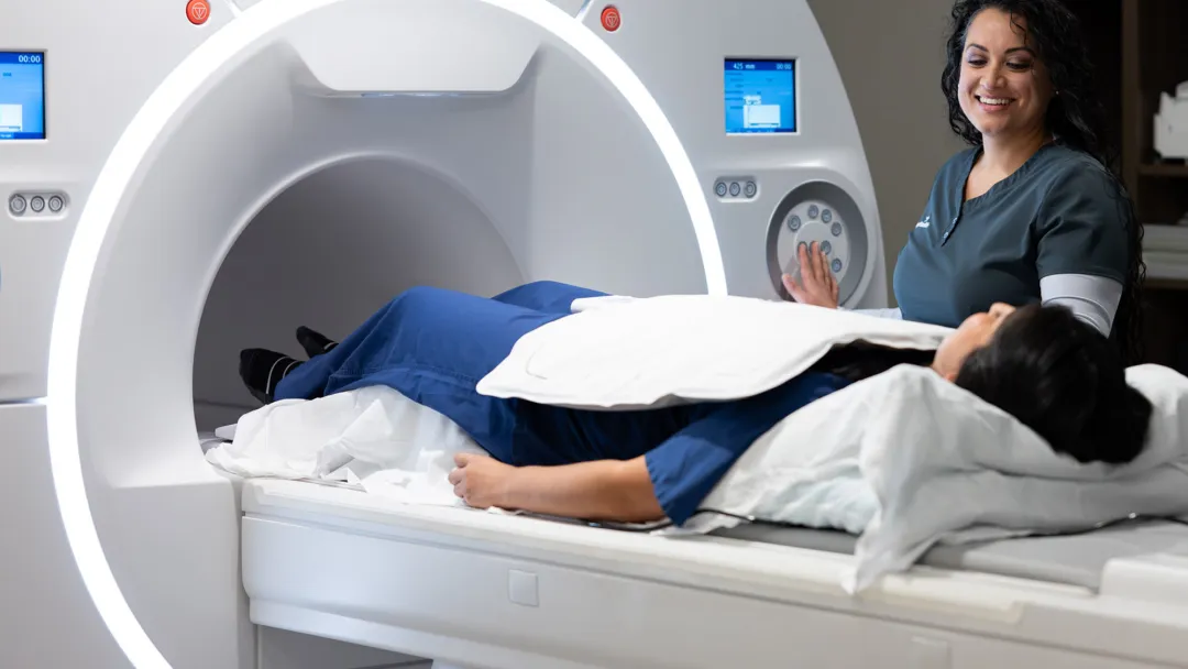 Patient going inside a MRI machine with the help of a nurse.