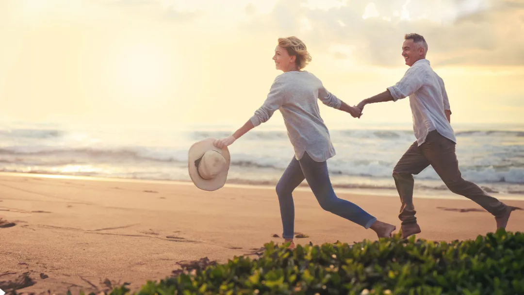a couple running on the beach at sunset holding hands