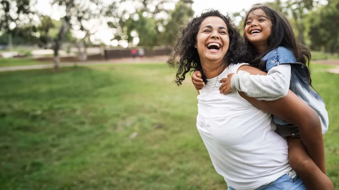 Mother with daughter on back outside