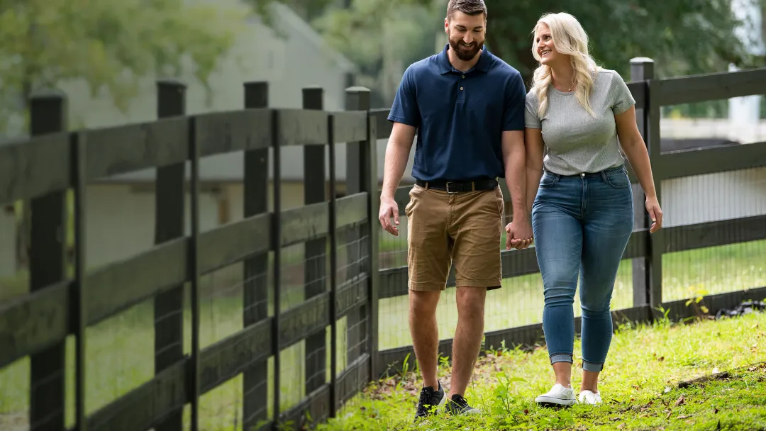 man and woman walking along a fence and smiling