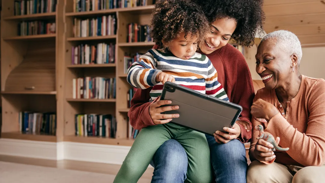Mother, grandmother and child looking at a tablet at home.
