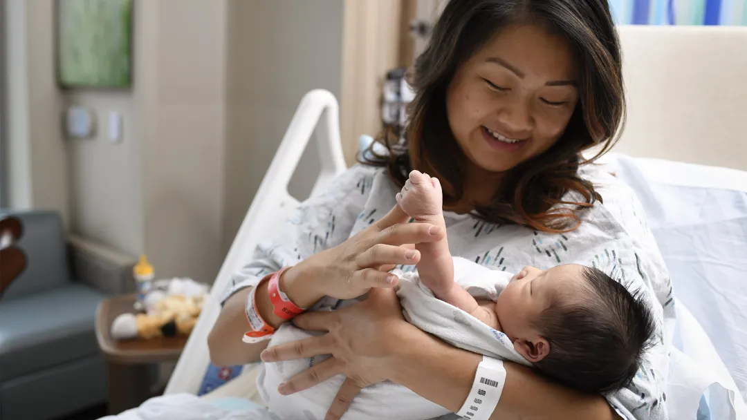 Mother holding her newborn baby in a hospital bed