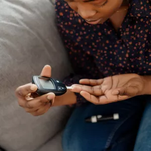 A Woman Tests Her Blood Sugar with a Finger Prick Glucose Device
