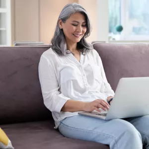 A woman using her computer while sitting on the couch.