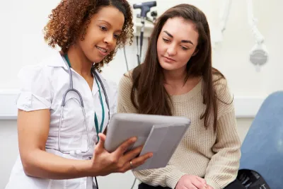A nurse shows a young woman her test results from a prevenetive screening.