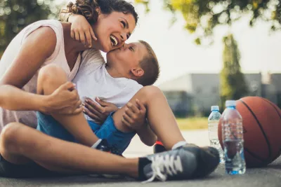 A mother and son take a water break on the basketball court during the summer.