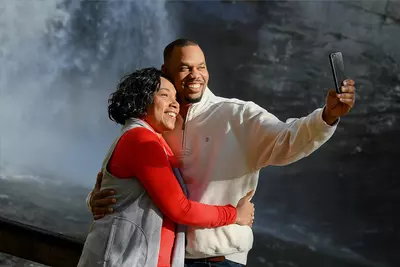 Couple taking a selfie in front of a waterfall.