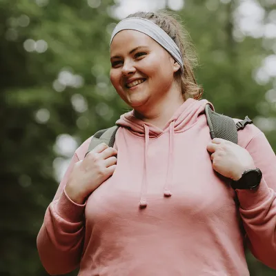 Woman smiling while she is on a hike outdoors.