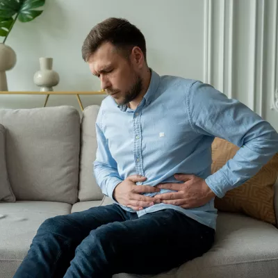 A Man Winces in Pain as He Hold's his Side