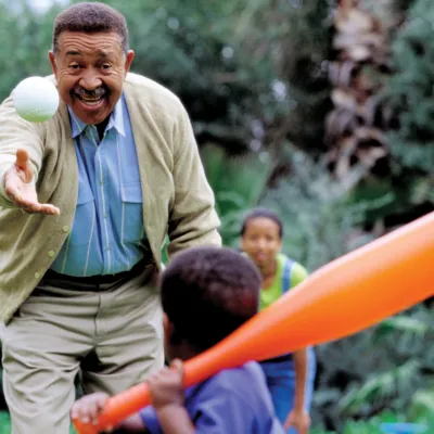 Grandfather playing a game of baseball with his grandson. The mother is behind them.