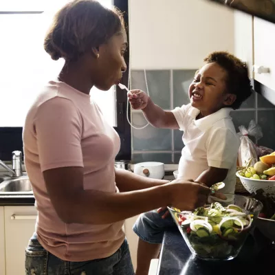 A mom prepares a meal for her family with the help of her toddler.