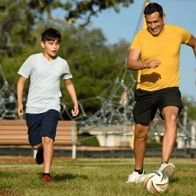 A father and son playing soccer.