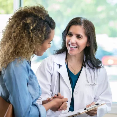 Doctor holding a clipboard and holding hands with a patient
