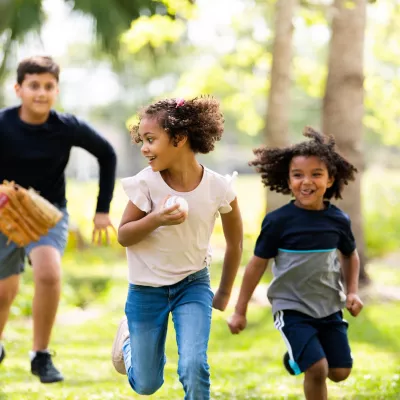 Three Hispanic Children Play Baseball in a Park