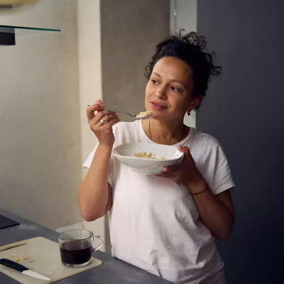 A hispanic woman eating a bowl of food.