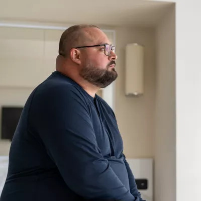 A man sitting at home looking onward.