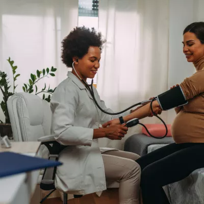 Pregnant woman getting her blood pressure checked by a physician