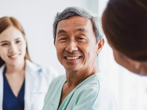 Patient smiling while a nurse holds his arm