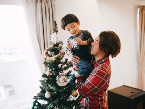 Father and son decorating a Christmas tree.