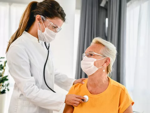 A doctor listens to a patient's breathing with a stethoscope