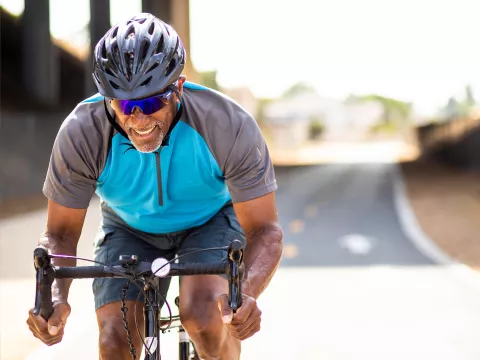 A Middle Aged Man Rides a Bicycle on a Road while Dressed in Typical Cyclist Attire.
