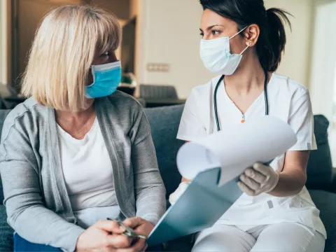 A Health Care Professional Goes Over Paperwork with a Patient in the Waiting Room.