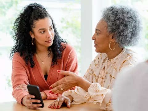 Mother and Daughter Have a Discussion in the Kitchen While Holding a Cell Phone