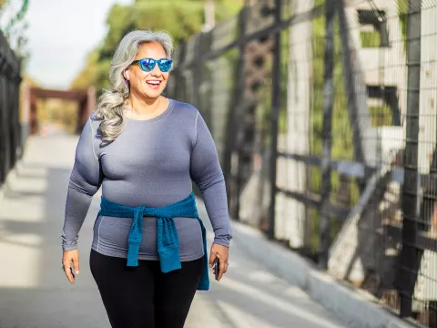 A Woman Walks Across a Pedestrian Bridge in the Fall