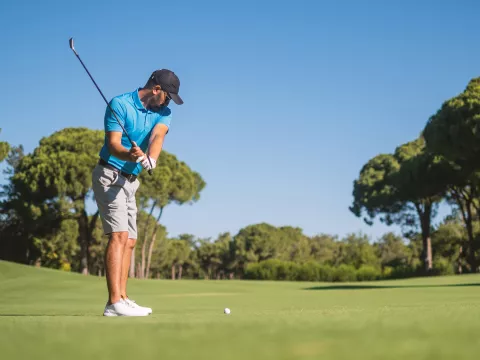 A Man Playing Golf with His Club in the Back Swing of His Approach to the Green.