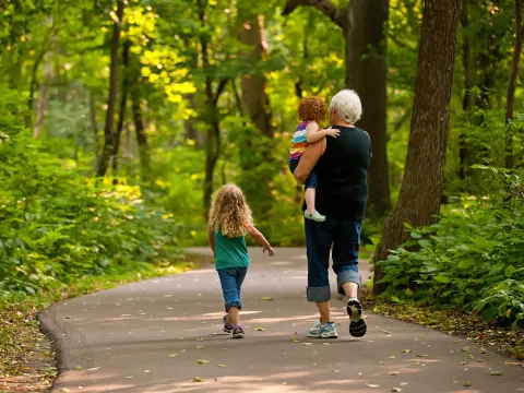 A Grandmother Walks 2 of her Grandchildren on a Path Through a Forest.