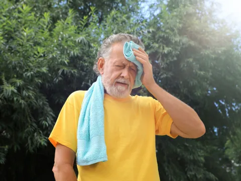 A Man Wipes the Sweat From His Forehead on a Hot Summer Day