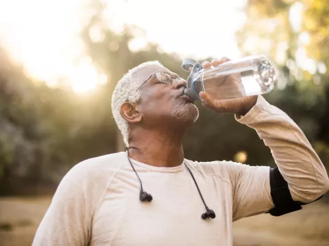 A Senior Man Drinks Water from a Reusable Water Bottle During a Break From His Run.