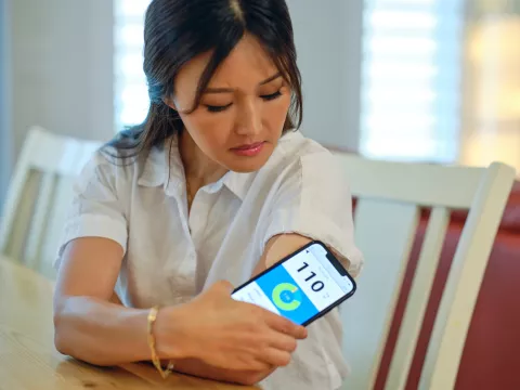 A Woman Checks Her Blood Sugar Levels at Her Kitchen Table.