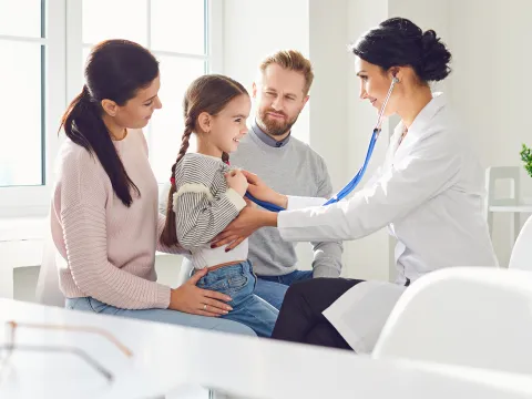 Doctor interacting with child patient with parents