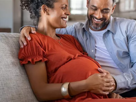 Pregnant couple sitting on couch