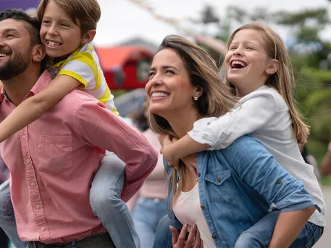 Two parents carrying on their backs their son and daughter.