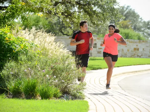 Smiling couple running outside on a sidewalk