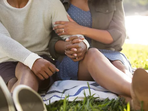 Couple holding hands on picnic blanket near the water