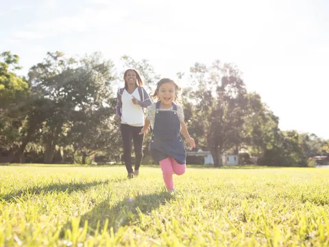 Daughter running ahead of mom outside. 