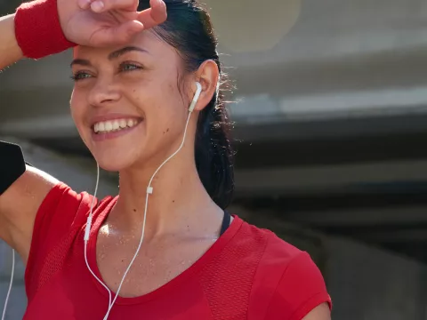 A woman with headphones in, dries off her forehead post workout.