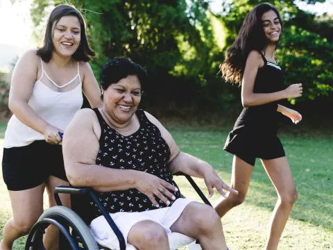 A woman in a wheelchair enjoys the outdoors with her daughters during the summer.