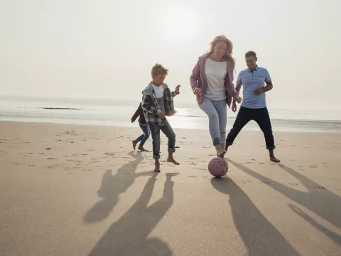 A family plays a friendly game of soccer on the beach