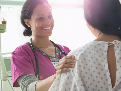 Female nurse comforting a female patient.