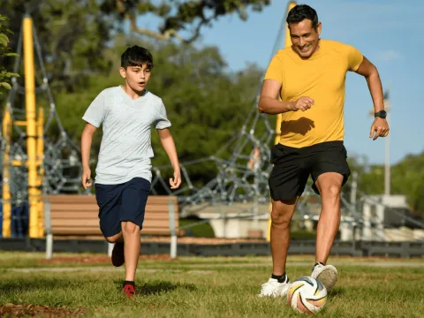 A father and son playing soccer.