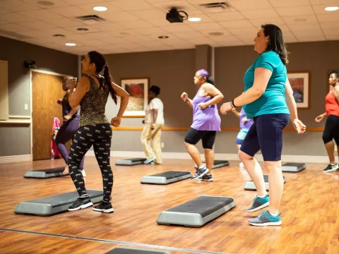 A group of women taking a step class at the gym.