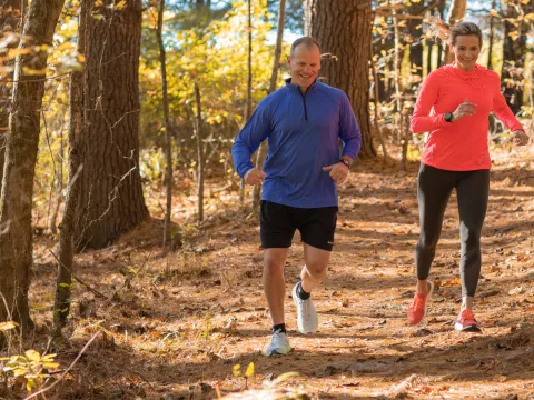 A Middle Aged Couple Goes For a Jog Through a Wooded Trail.