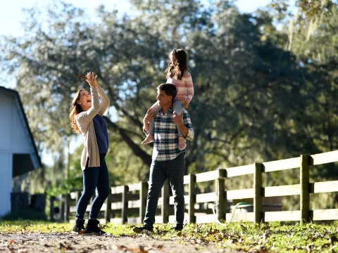 A mother, father, and small daughter walking around a ranch