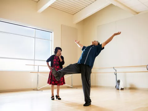 Friends are dancing while putting their arms in the air at a dance studio. 